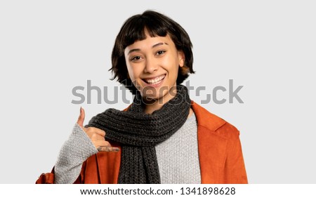 Short hair woman with coat making phone gesture. Call me back sign on isolated grey background