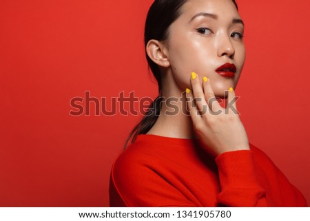 Portrait of attractive young asian woman with beautiful make up on red background. Asian female model with red top and lipstick.
