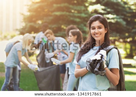 Volunteering, charity and ecology concept. Happy woman and group of volunteers with garbage bags cleaning area in park, free space Royalty-Free Stock Photo #1341917861