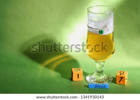 A glass of beer and calendar cubes on green background 3