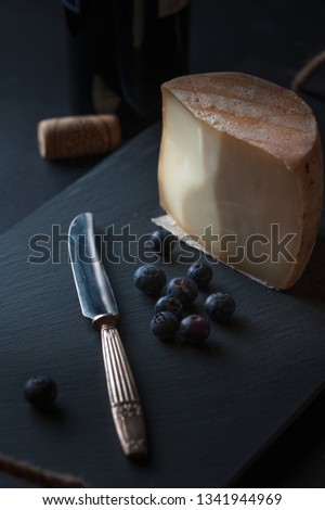 cheese board with hard mature cheese, antique knife and blueberries. Selective focus.