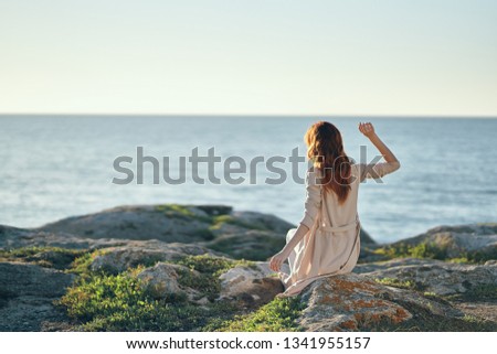 Pretty woman in nature sitting on the rocks near the ocean vacation
