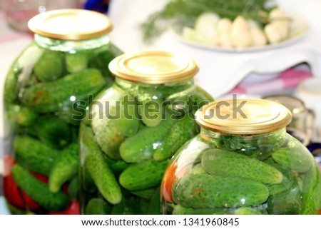 Harvesting cucumbers and tomatoes for the winter in rural conditions, laying vegetables in a glass jar