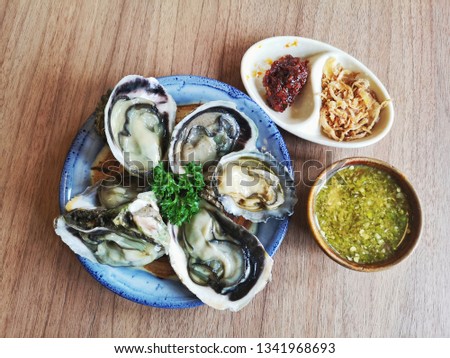 Fresh oysters in a plate and seafood In the plate placed on a wooden floor.