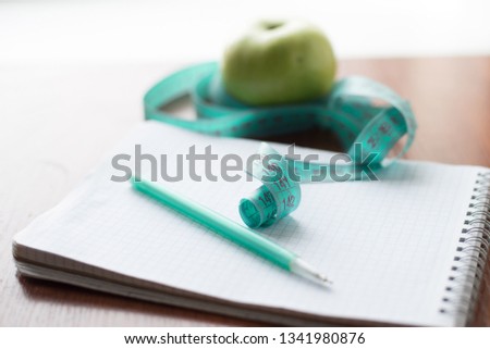 apple and a notebook on a wooden background.Diet concept. health.an apple and pen, closeup.