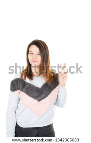 Teenager girl on white background smiling and showing victory sign with hand fingers