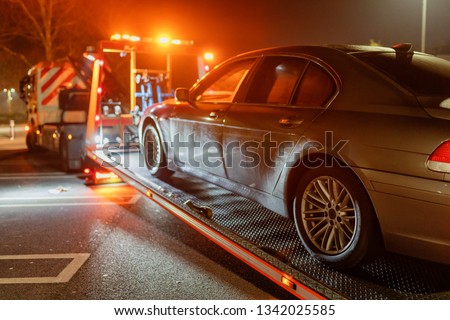 Road rescue service truck picking up a saloon car Royalty-Free Stock Photo #1342025585