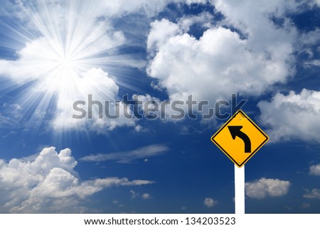 Direction sign- left turn sign pointing to rays of light on blue sky background