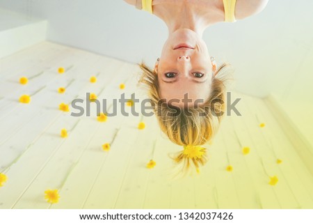 cheerful girl upside down against the background of hanging dandelions