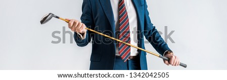 panoramic shot of mature man in suit holding golf club isolated on grey