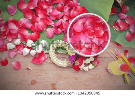 Songkran traditional festival or Thai New Year in 13th April decorative background with fresh petal rose flower, garland, white clay filler, aromatic water with petal rose in silver bowl on lotus pad 