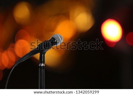 Modern microphone on stand against blurred background, space for text