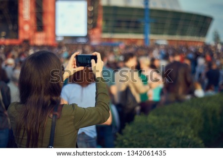 Girl with a phone in her hands in a crowd at an open concert