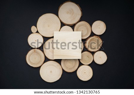 Pine tree cross-sections with annual rings and wooden square onblack surface. Lumber piece close-up shot, top view.