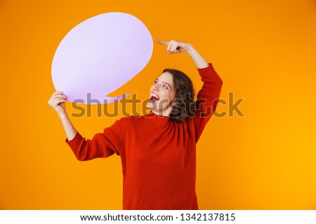 Image of feminine girl 20s wearing sweater holding thought bubble with copyspace while standing isolated over yellow background