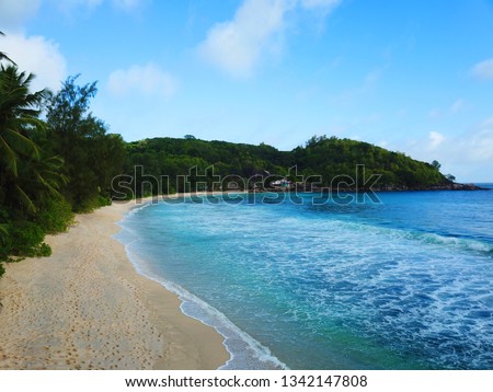 Coastline of the Takamaka beach at the tropical Seychelles. This picture contains Palms, the beach, a beach bar and a coral reef under the Water.