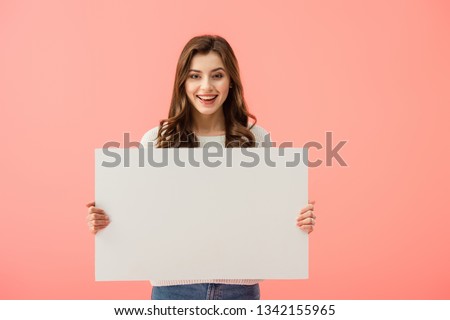 smiling and attractive woman holding empty board with copy space isolated on pink Royalty-Free Stock Photo #1342155965