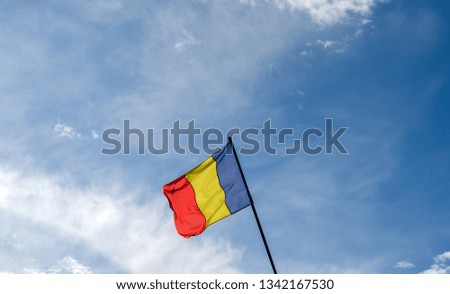 Low angle view of Romania flag  agains cloudy  blue sky.