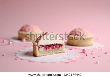 Mousse mini tarts covered with pink velvet spray decorated with sugar balls on pink background