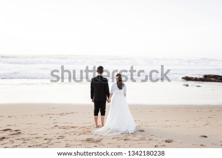 Bride and groom looking at the ocean on the beach