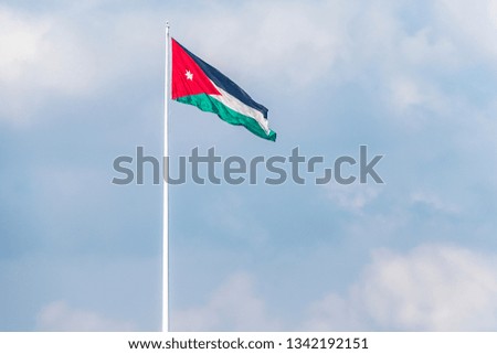  flag of Jordan on the background of the gloomy sky waves in the wind.
selective focus