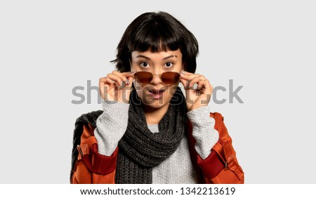 Short hair woman with coat with glasses and surprised on isolated grey background