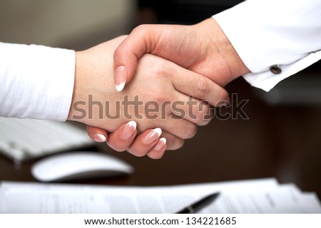 Business handshake: two businesswomen handshaking over table with  agreement
