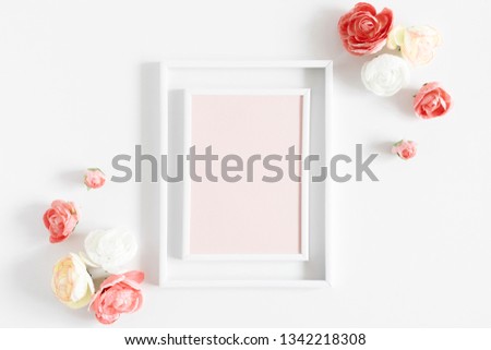 Flowers composition creative. Blank photo frame, pink flowers on white background. Flat lay, top view, copy space