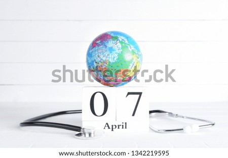 Stethoscope and globe with April 7 text wooden block calendar on white wooden background. World Health Day concept.
