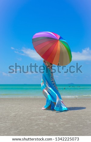 A girl with a rainbow umbrella on the beach