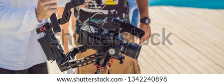 Professional steadicam operator uses a 3-axis camera stabilizer system on a commercial production set BANNER, LONG FORMAT