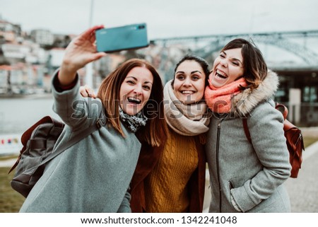 
Three beautiful and funny women traveling together in Porto, Portugal. Taking photos as memories of their trip, carefree and relaxed. 