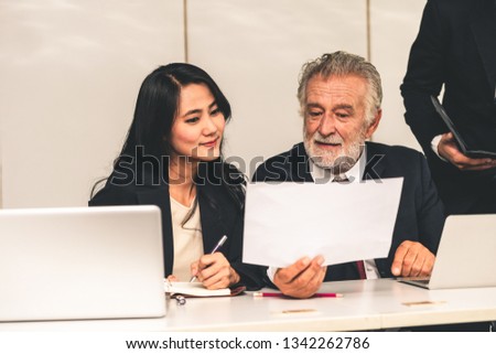 Senior caucasian manager working in office with assistance of young Asian business people and translator in the meeting. Corporate international business and secretary language translation concept.