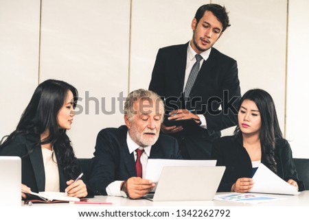 Senior caucasian manager working in office with assistance of young Asian business people and translator in the meeting. Corporate international business and secretary language translation concept.