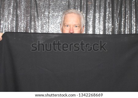 Man in a Photo Booth. A man smiles and poses with a black table cloth in a Photo Booth. Photo Booths are fun for all guest. 