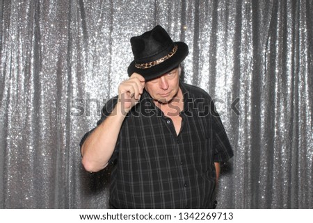 Man in a Photo Booth. A man smiles and poses in a Photo Booth with silver sequin curtains. Photo Booths are fun for all guest. 