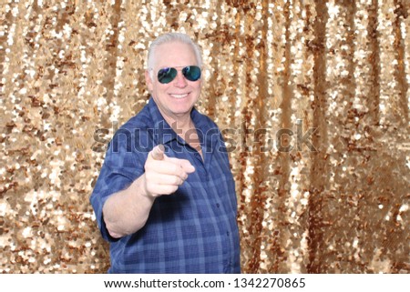 Man in a Photo Booth. A man smiles and poses in a Photo Booth with Gold Sequin Curtains. Photo Booths are fun for all guest. 