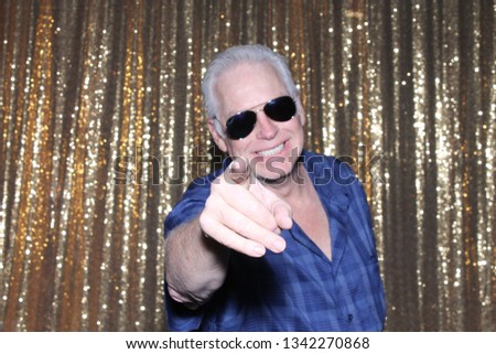 Man in a Photo Booth. A man smiles and poses in a Photo Booth with Gold Sequin Curtains. Photo Booths are fun for all guest. 