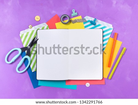Bright office supplies, school stationery, white notepad on the table, purple background. Back to school concept. Top view. Copy space