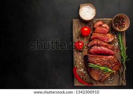 
Beef steak, herbs and spices on a cutting board on a background of stone, top view copy space for your text