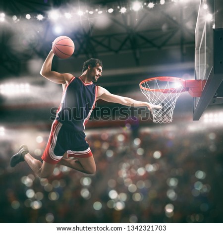 Acrobatic slam dunk of a basket player in the basket at the stadium