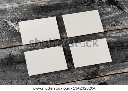Mockup of four white blank business cards at wooden vintage table background.