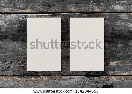 Mockup of two white vertical blank business cards at wooden vintage table background.