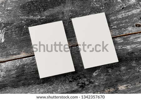 Mockup of two white vertical blank business cards at wooden vintage table background.