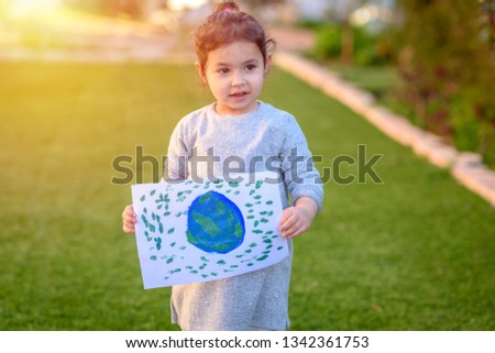 Portrait of the cute little girl holding the drawing earth globe outdoor sunny day. Child drawng a picture of earth.