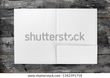 Top view mockup of white opened presentation folder and letterhead at vintage wooden table background.