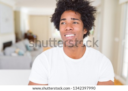 African American man at home smiling looking side and staring away thinking.
