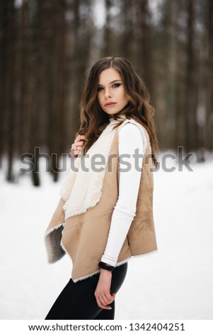 Portrait of a stylish young girl on the background of a snowy forest
