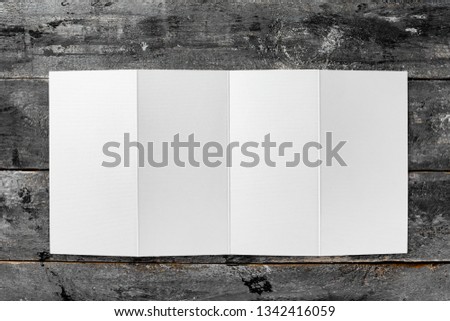 Top view mockup of white opened four fold blank brochure at wooden vintage table background.