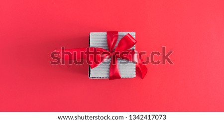 Gift with red satin bow on red background. Christmas. Wedding. Birthday. Happy womens day. Mothers Day. Valentine's Day. Flat lay, top view, copy space, banner